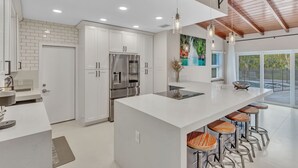 A modern kitchen with white cabinets, stainless steel appliances, and a large island with bar stools. - Hidden Getaway Pool Home on 1.5 acres near all. Sleeps 17. Pool, ping pong etc. (Fort Lauderdale)