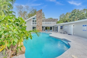A swimming pool with a stone wall and a two-story building in the background.