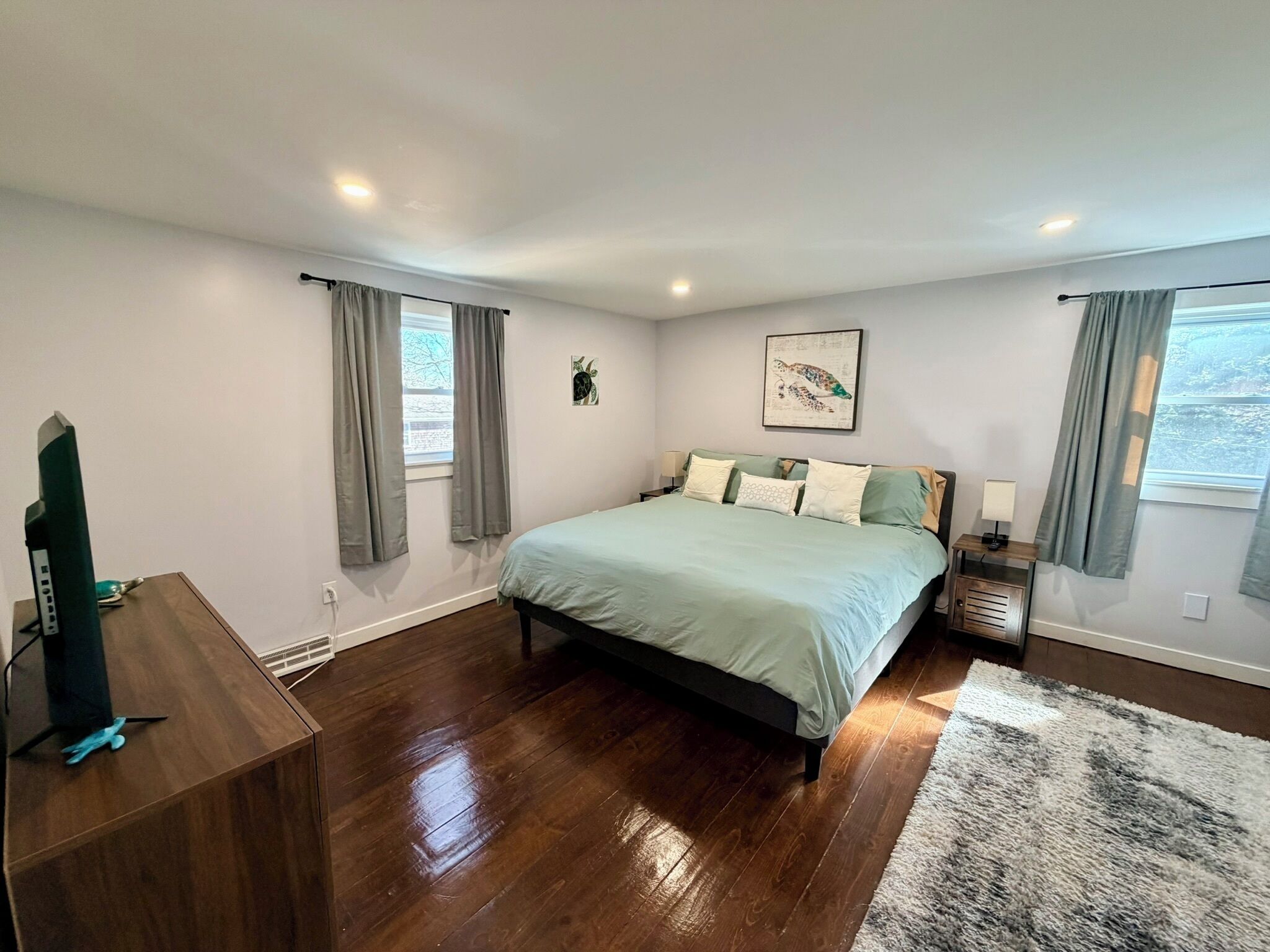 Quarto com cama, escrivaninha e janela com cortinas.