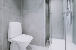 Een moderne badkamer met toilet, douchecabine en grijze betegelde wanden.