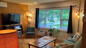 Una sala de estar moderna con un televisor de pantalla plana, un sofá cómodo, una mesa de centro de madera y un ventanal con vistas al exterior.