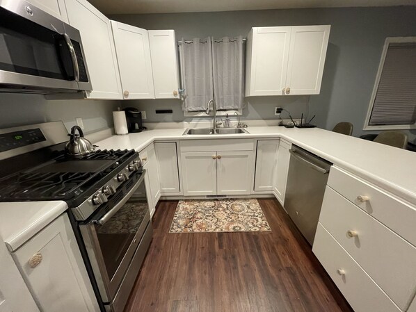 A kitchen with white cabinets, a stove, a microwave, and a dishwasher.