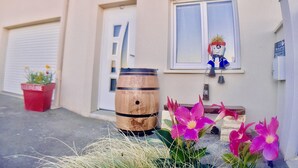 Ein Gebäude mit einer Garagentür, einem Holzfass, einer Bank und einem Fenster mit einer Person.