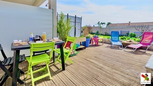Eine Terrasse im Freien mit Tisch und Stühlen, eine Holzterrasse und ein Gartenbereich.