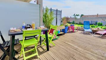 Een buitenpatio met een tafel en stoelen, een houten terras en een tuin.