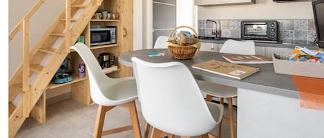 A modern kitchen with a built-in microwave, a large island with seating, and a wooden staircase leading to a loft area.