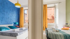 A hotel room with a bed, a nightstand, a lamp, and a view of the city through the window. - Rome Centro-Repubblica Apartment  (Roma)