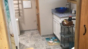 A compact kitchen with a blue bowl sink, a calendar, and a wooden door. - Jaggi Swiss Gasthaus  (Monticello)