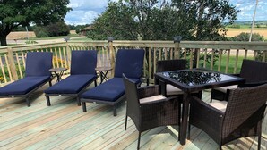 A wooden deck with outdoor furniture including lounge chairs and a table. - Jaggi Swiss Gasthaus  (Monticello)