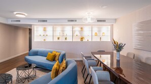 Un salon moderne avec un canapé bleu, une table à manger et une vitrine en verre contenant des objets décoratifs.