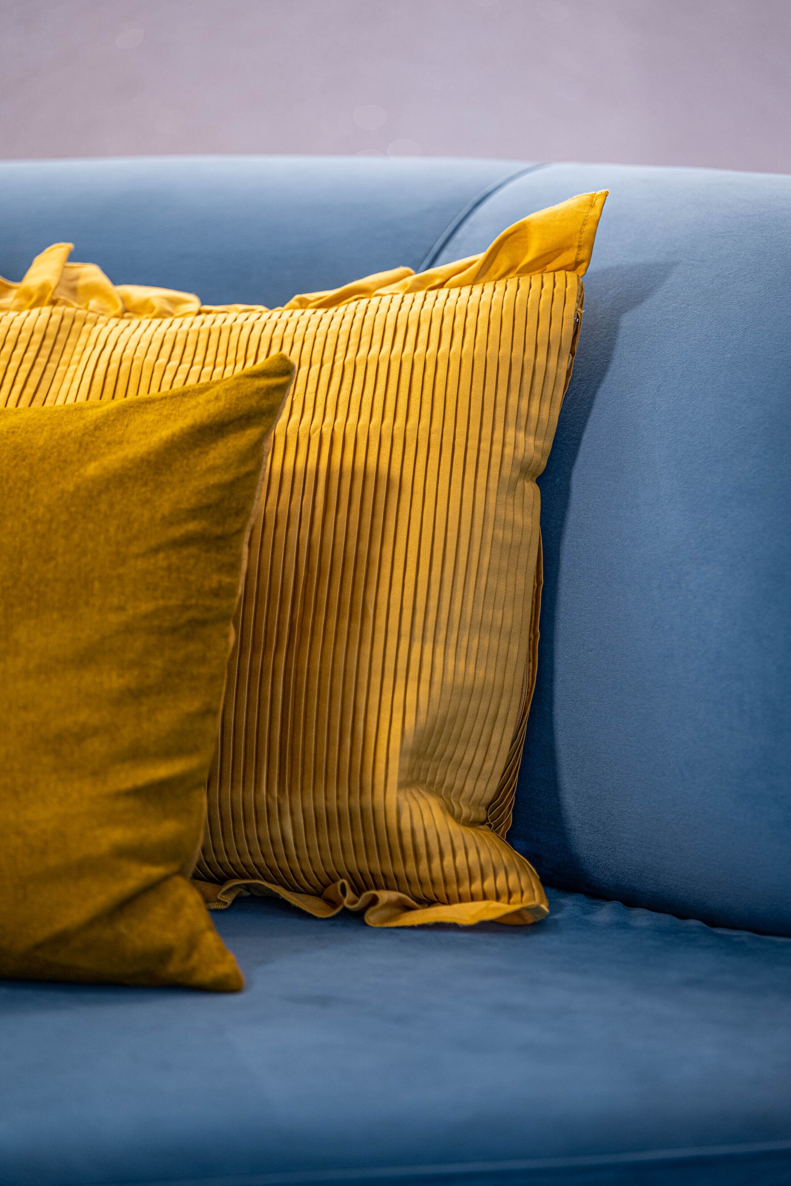 Ein blaues Sofa mit zwei gelben Kissen.