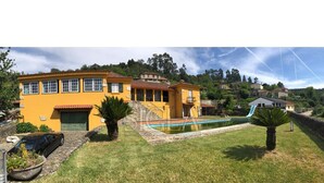 A yellow house with a swimming pool, a car, and a small garden. - House with pool and barbecue (Valença)