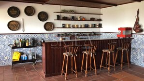 A bar area with stools, shelves with bottles, and decorative plates on the wall. - House with pool and barbecue (Valença)