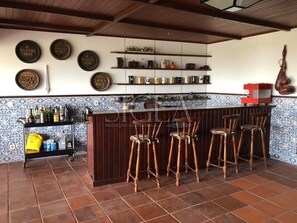 A bar area with stools, shelves with bottles, and decorative plates on the wall.