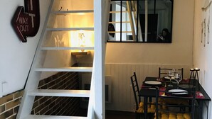 Un escalier menant à une salle à manger où une table est dressée pour deux personnes.