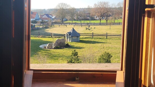 A window view of a rural landscape with a small house, open fields, and a clear sky. - Cozy vacation apartment for 1 to 4 people. Perfect for a little time out  (Frielendorf)