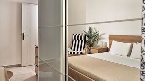 A modern bedroom with a bed, bedside table, lamp, and a potted plant. - One Bedroom Apartment (Zakynthos)