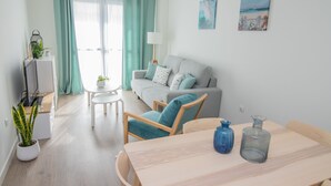 A modern living room with a sofa, a dining table, and a TV. - SUITE MARINA BEACH COSTA DEL SOL (Fuengirola)
