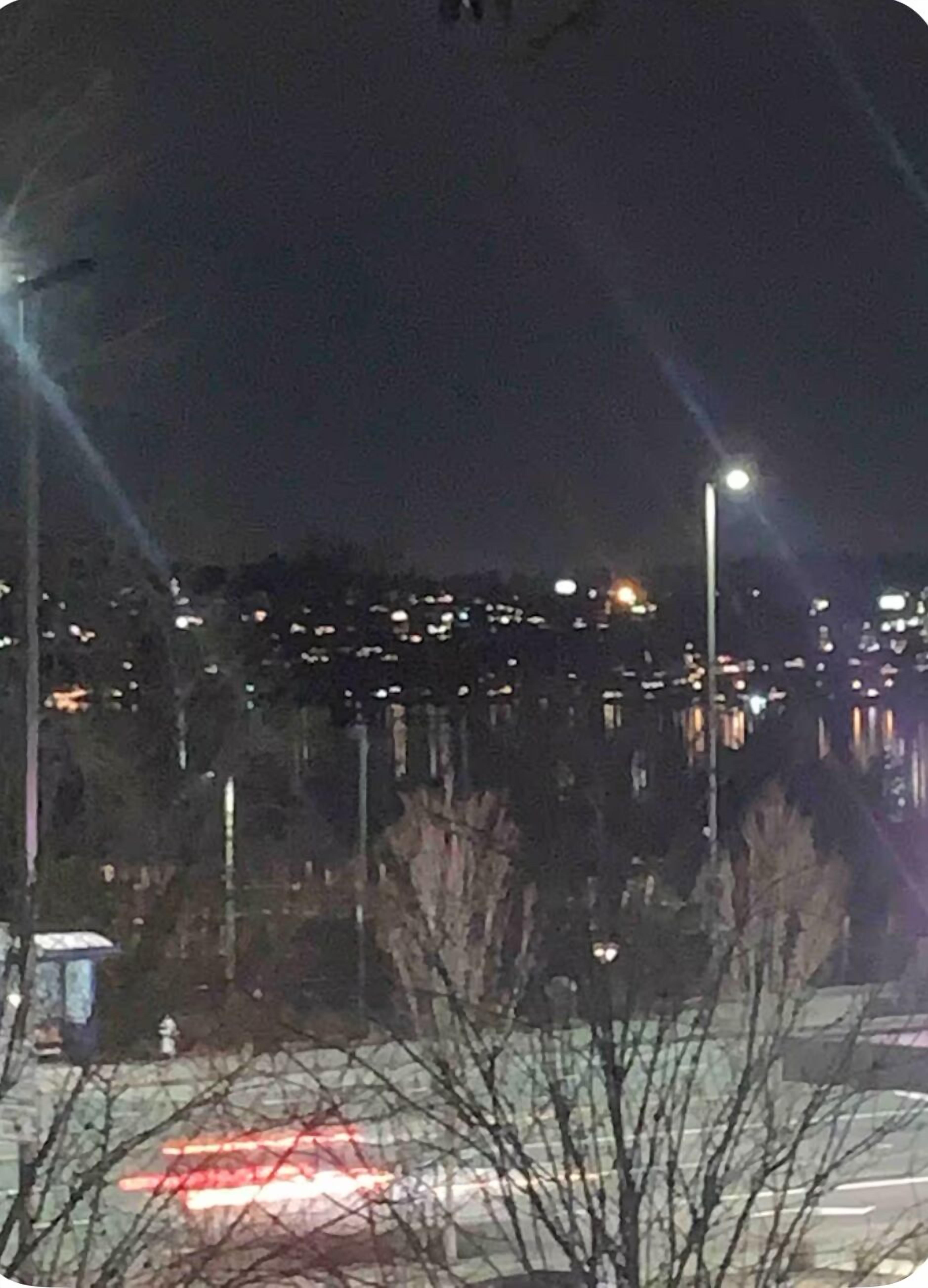 A nighttime view of a cityscape with streetlights and distant buildings.