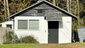 A small, single-story building with a gabled roof and a garage door. - Cozy 1BR Cottage Near Lake, Trails & City Access (Kenmore)