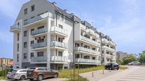 Ein mehrstöckiges Wohngebäude mit Balkonen, einem Parkplatz und blauem Himmel.