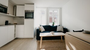 Eine kompakte Küche mit weißen Schränken, einem eingebauten Ofen und einem Essbereich mit einem Holztisch und Stühlen.