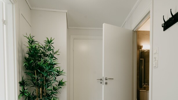 Ein Flur mit einem Blumentopf, einer Bank und einer zur Toilette führenden Tür.