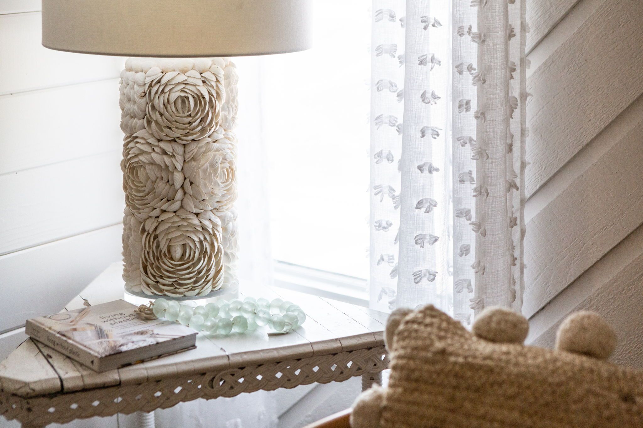 Een lamp met bloemendecoratie, een boek en een glazen object op een tafel.