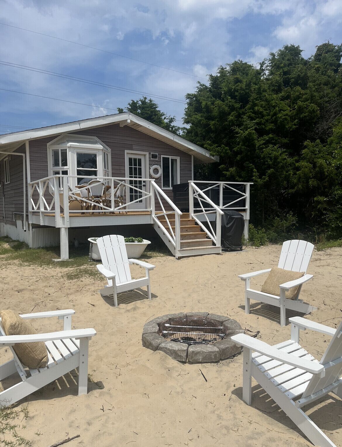 Une maison de plage avec une terrasse, un espace salon extérieur et un foyer.