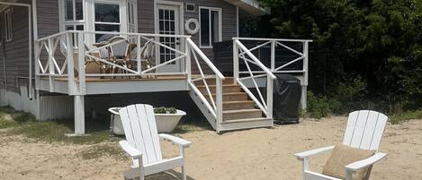 Une maison de plage avec une terrasse, un espace salon extérieur et un foyer.