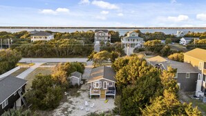 Zona residencial costera con casas, una playa arenosa y un puente al fondo.