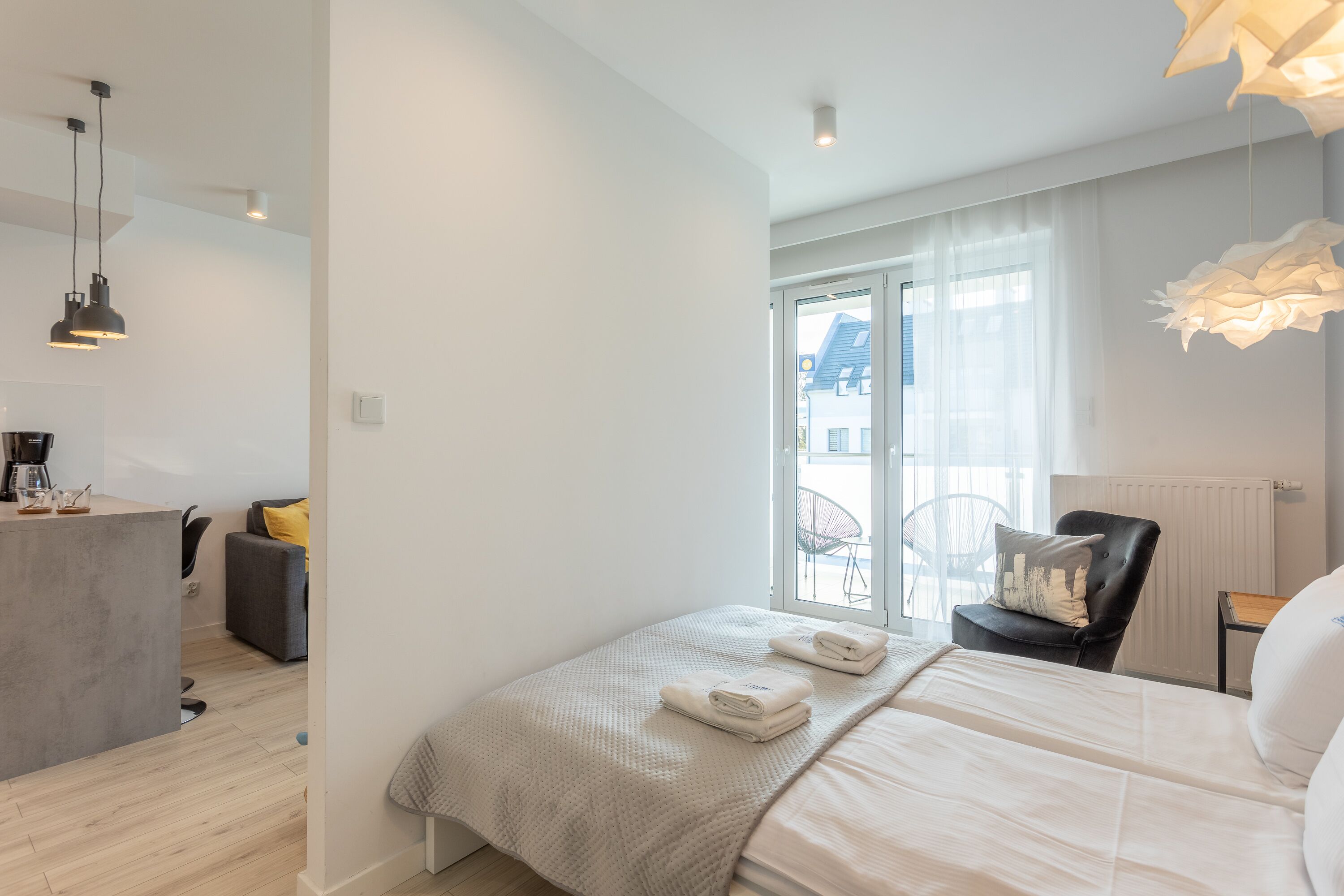 Ein modernes Hotelzimmer mit Bett, kleinem Schreibtisch, Stuhl und einem Balkon mit Blick.