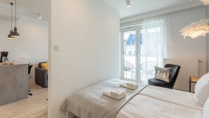 Een moderne hotelkamer met een bed, een klein bureau, een stoel en een balkon met uitzicht.
