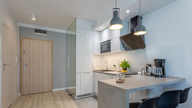 Een moderne keuken met een centraal eiland, barkrukken, een magnetron en een koffiezetapparaat.