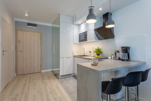 Une cuisine moderne dotée d’un îlot central, de tabourets de bar, d’un four à micro-ondes et d’une machine à café.