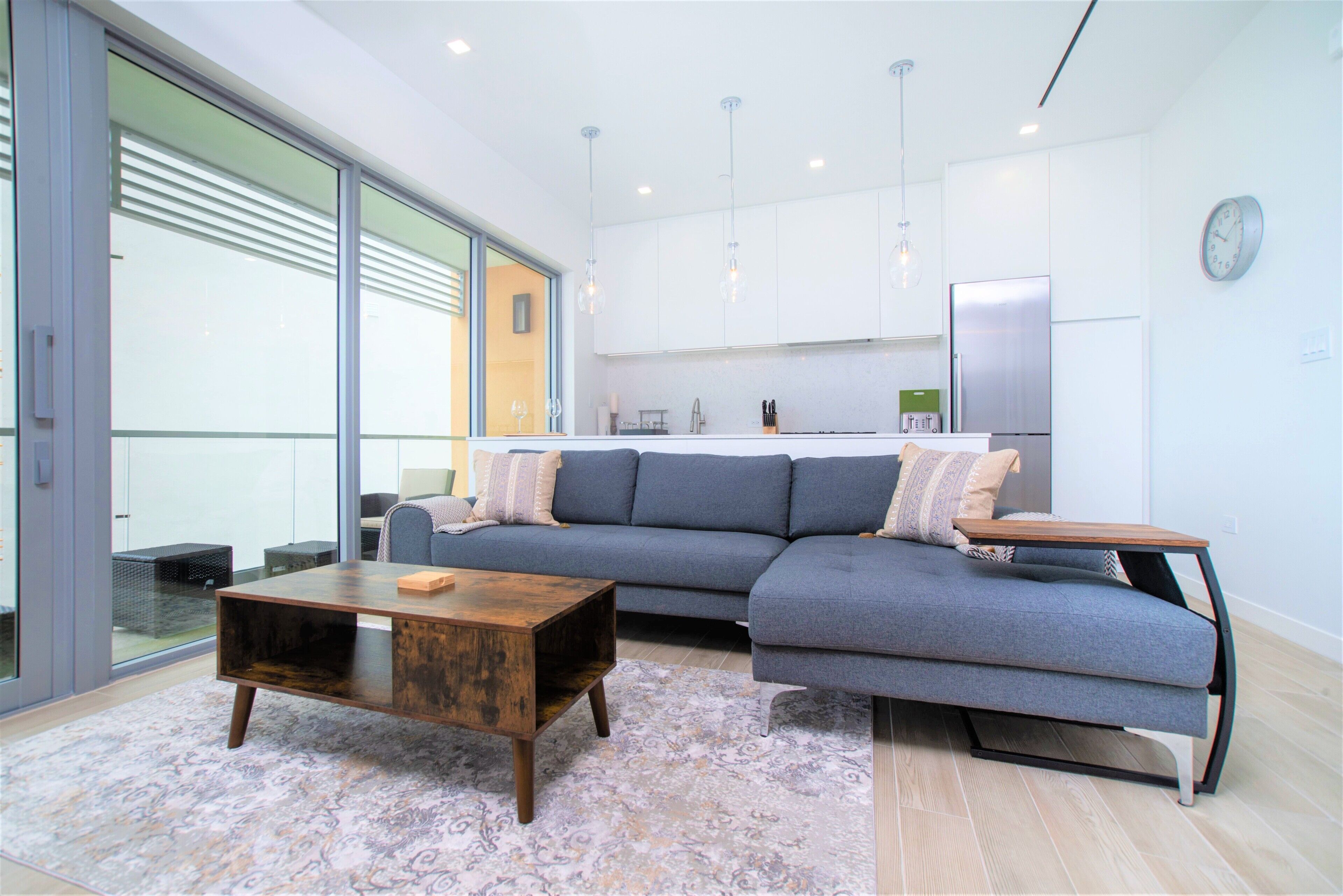 A modern living room with a sectional sofa, a wooden coffee table, and a patterned rug.