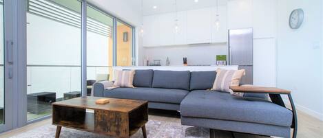 A modern living room with a sectional sofa, a wooden coffee table, and a patterned rug.