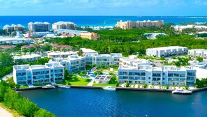 A coastal resort with modern buildings, a marina, and a view of the ocean. - Cayman Luxury Rentals at One Canal Point (Seven Mile Beach)