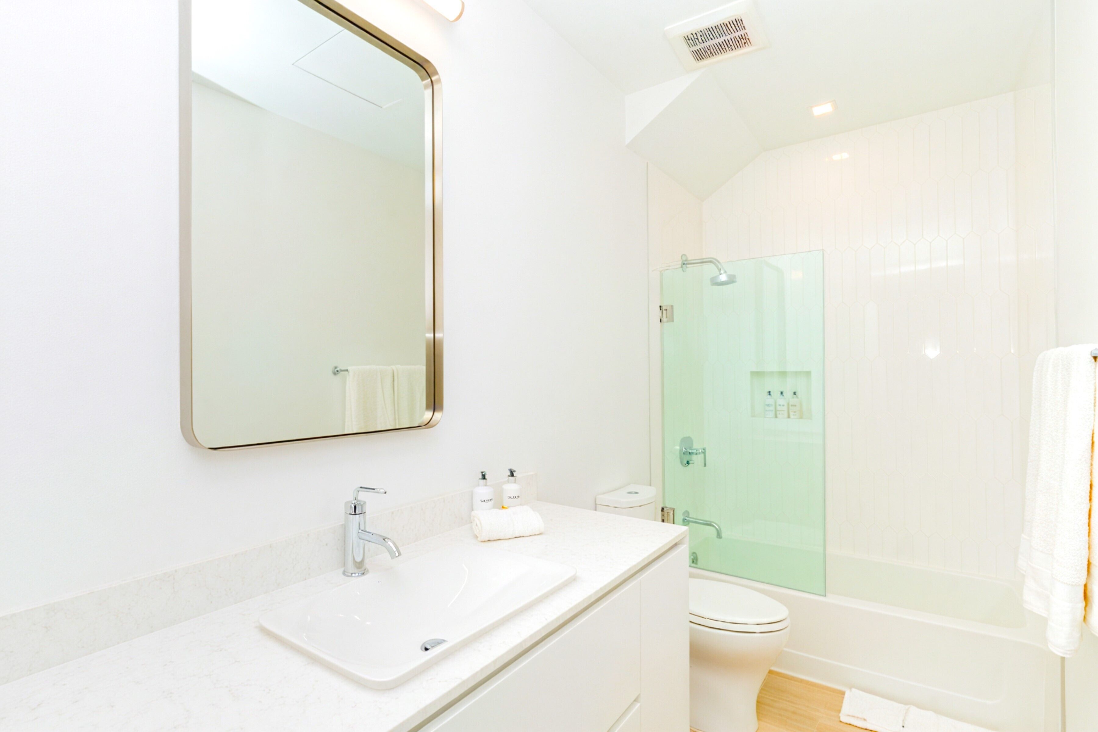 Een moderne badkamer met een grote spiegel, een wastafel, een toilet en een douche met glazen wanden.