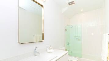 Een moderne badkamer met een grote spiegel, een wastafel, een toilet en een douche met glazen wanden.