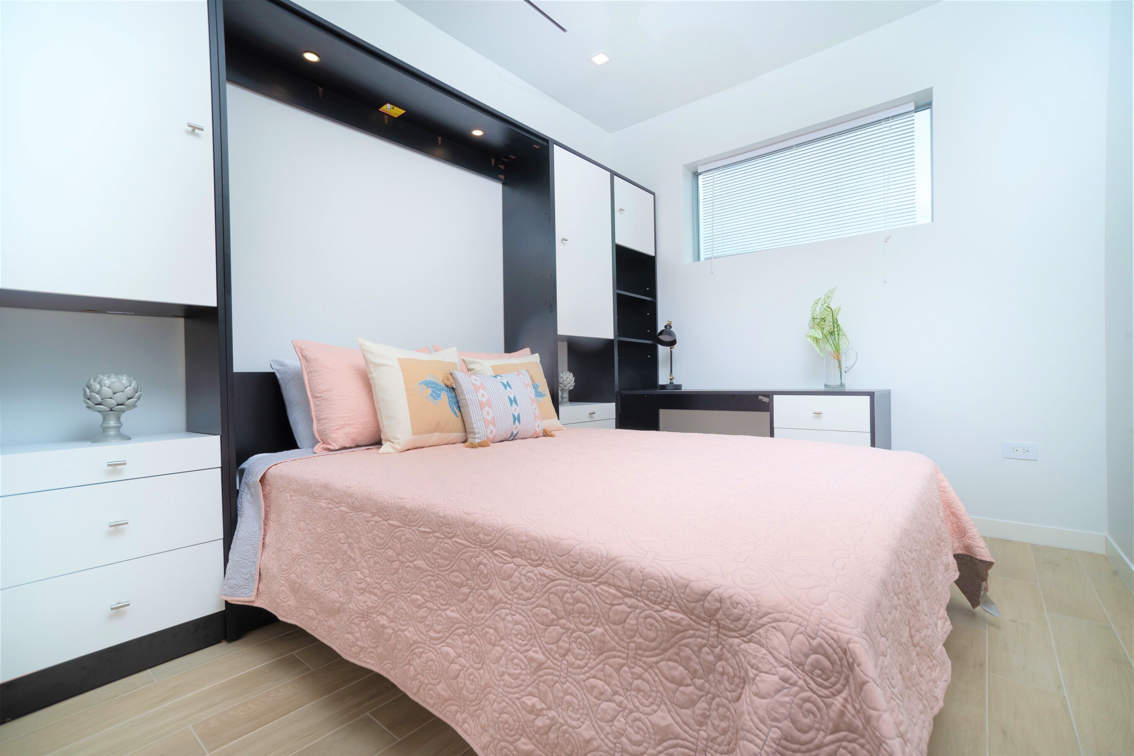 A bedroom with a bed, bedside tables, a mirror, and a window.