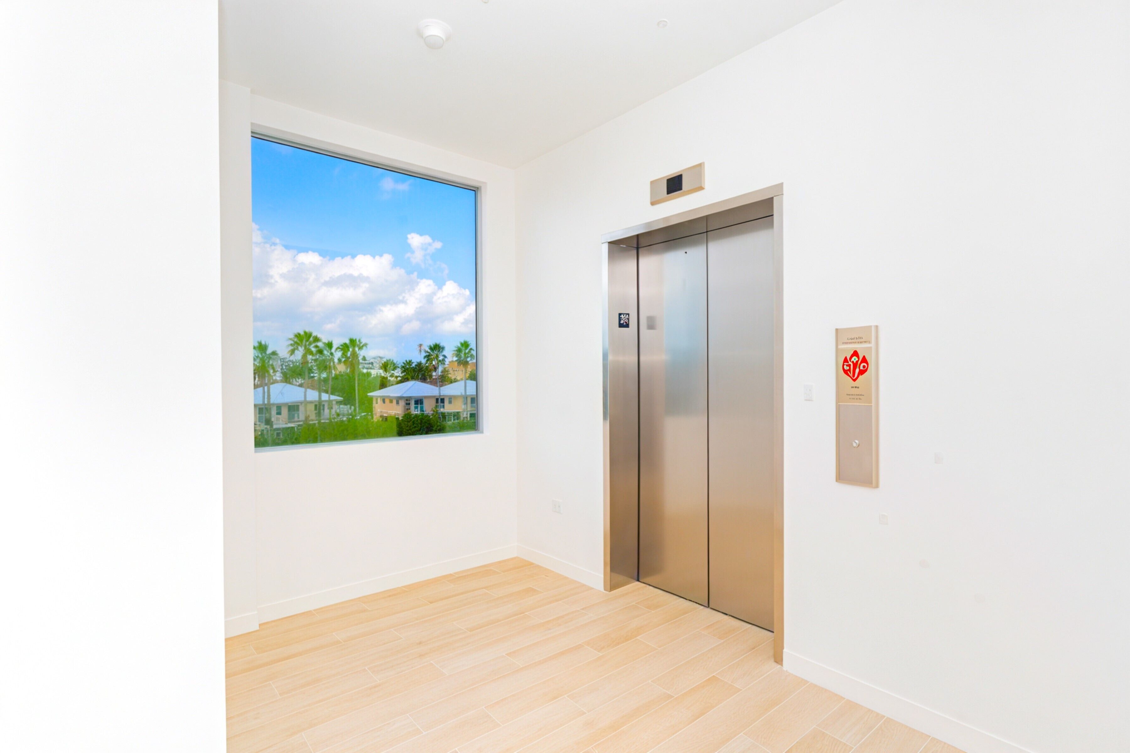 A modern elevator with a clear view of a residential area outside.