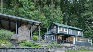 A two-story house with a stone chimney, a balcony, and a porch. - PENN STATE Country Creek Cottage w/ Hot Tub - ON Spring Creek and 7 miles to PSU (Bellefonte)
