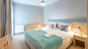 Quarto bem arrumado com cama, mesas de cabeceira, abajur e radiador.