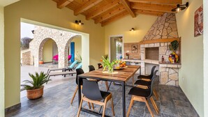 Un espace de restauration en plein air agrémenté d’une arche en pierre, d’un plafond en bois et d’une cheminée en pierre.