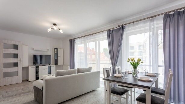 A modern living room with a sofa, dining table, and kitchen area. - Vacation apartment by the sea, vacation on the island of Usedom, Apartment FLOTYLLA 13 (Swinoujscie)