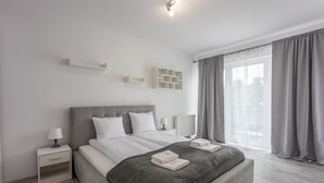 A modern bedroom with a large bed, bedside tables, and a view of the city through sheer curtains. - Vacation apartment by the sea, vacation on the island of Usedom, Apartment FLOTYLLA 13 (Swinoujscie)