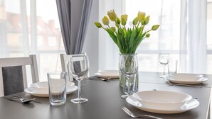 A dining table set with plates, glasses, and cutlery, a vase with flowers, and a chair with a picture frame. - Vacation apartment by the sea, vacation on the island of Usedom, Apartment FLOTYLLA 13 (Swinoujscie)