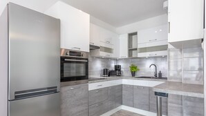 A modern kitchen with stainless steel appliances, grey cabinets, and a wooden floor. - Vacation apartment by the sea, vacation on the island of Usedom, Apartment FLOTYLLA 13 (Swinoujscie)