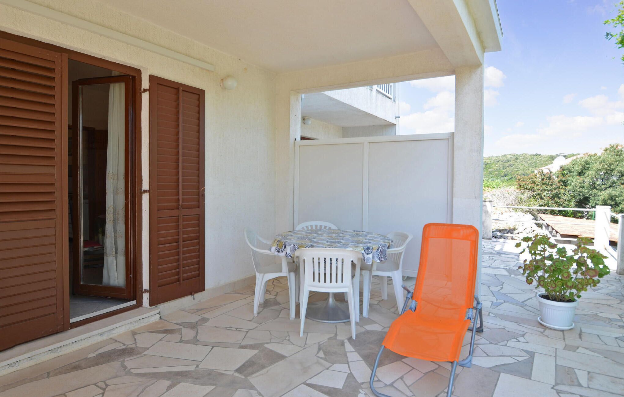 Un patio con una mesa, sillas, una puerta corrediza y una planta en maceta.